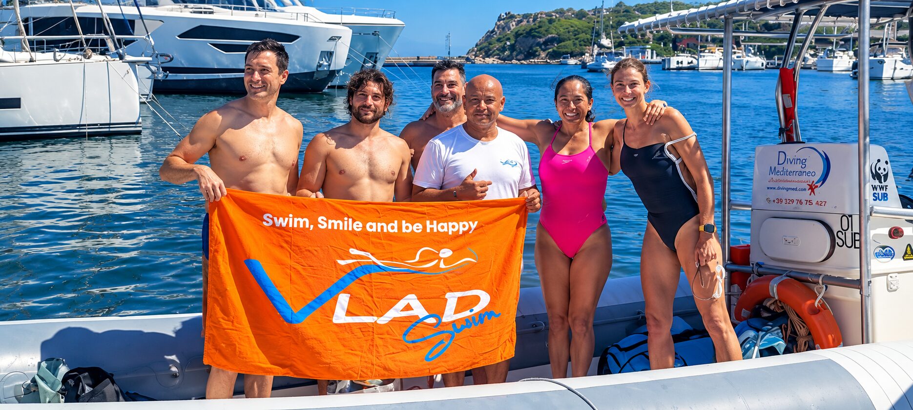 Six swimmers celebrating on their support boat with the orange Vladswim flag